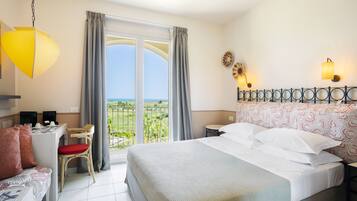 A hotel room with a bed, a desk, a chair, a sofa, a balcony with a view, and a hanging light fixture.