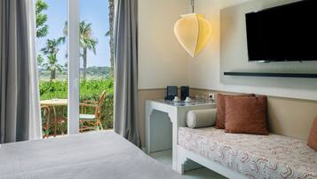Una camera d'albergo con un letto, un tavolino con una macchina del caffè, una televisione a muro e un balcone con tavolo e sedie.