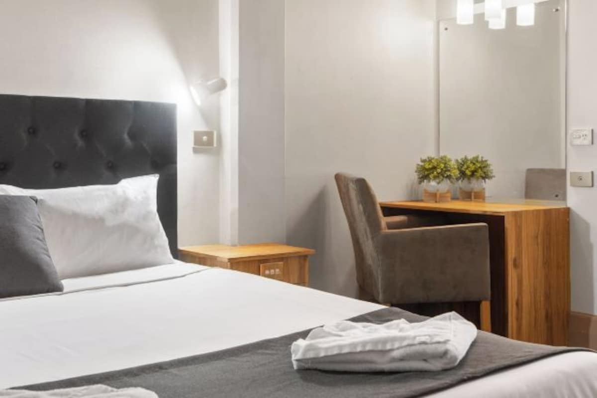 Una habitación de hotel con una cama, un escritorio y una silla.