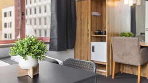 A modern room with a wooden desk, a potted plant, and a view of a building through a window.