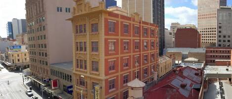 Um edifício de vários andares com fachada vermelha e amarela, um letreiro visível de 'Motel' e um sinal de 'Tab' indicando comodidades próximas.