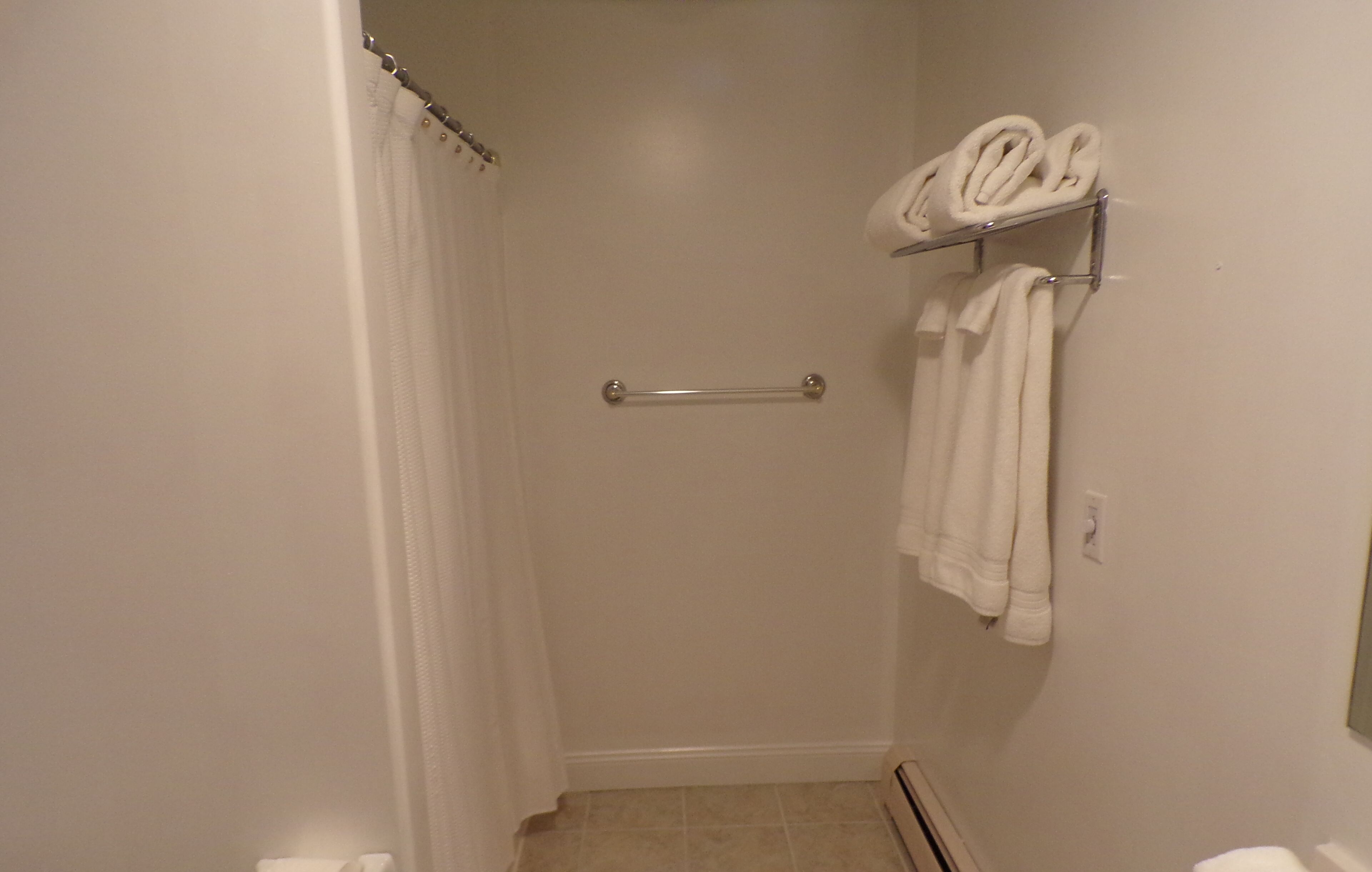 Ein Badezimmer mit Dusche, Handtuchhalter und Toilette.