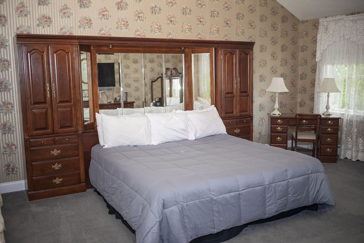 Une chambre à coucher avec un grand lit, une armoire en bois et un bureau avec une chaise.