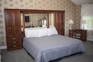 Un dormitorio con una cama grande, un armario de madera y un escritorio con una silla.
