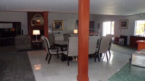 A spacious living room with a dining area, featuring a fireplace, a television, and a large window. - Long House Manor B And B (Watkins Glen)