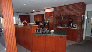 A kitchen with wooden cabinets, a brick wall, and a built-in oven. - Long House Manor B And B (Watkins Glen)