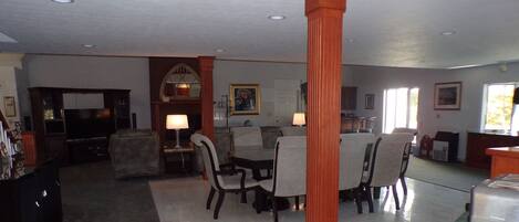 A spacious living room with a dining area, a fireplace, and a kitchen in the background.