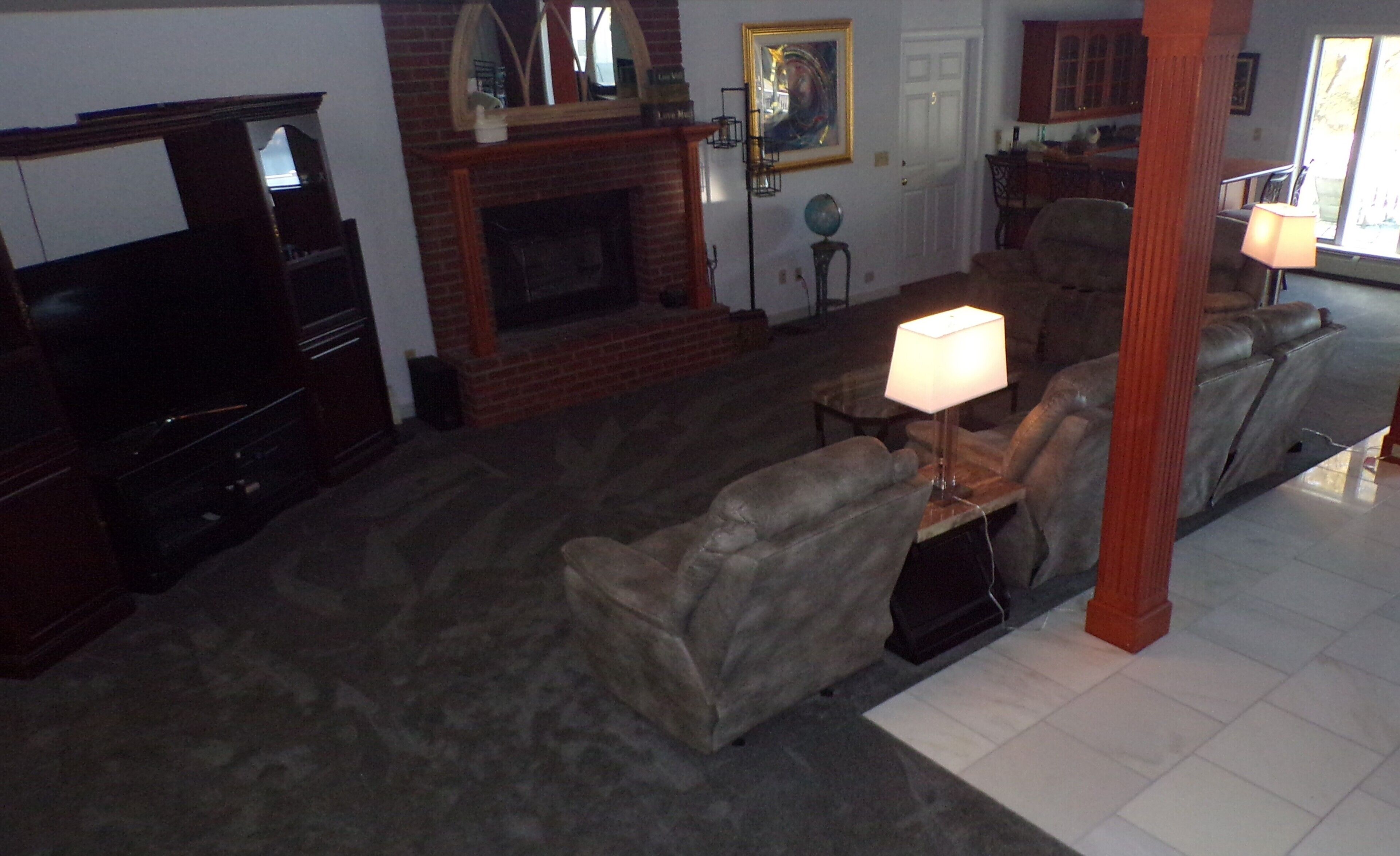 Una sala de estar con chimenea, un sofá, un televisor y una lámpara.