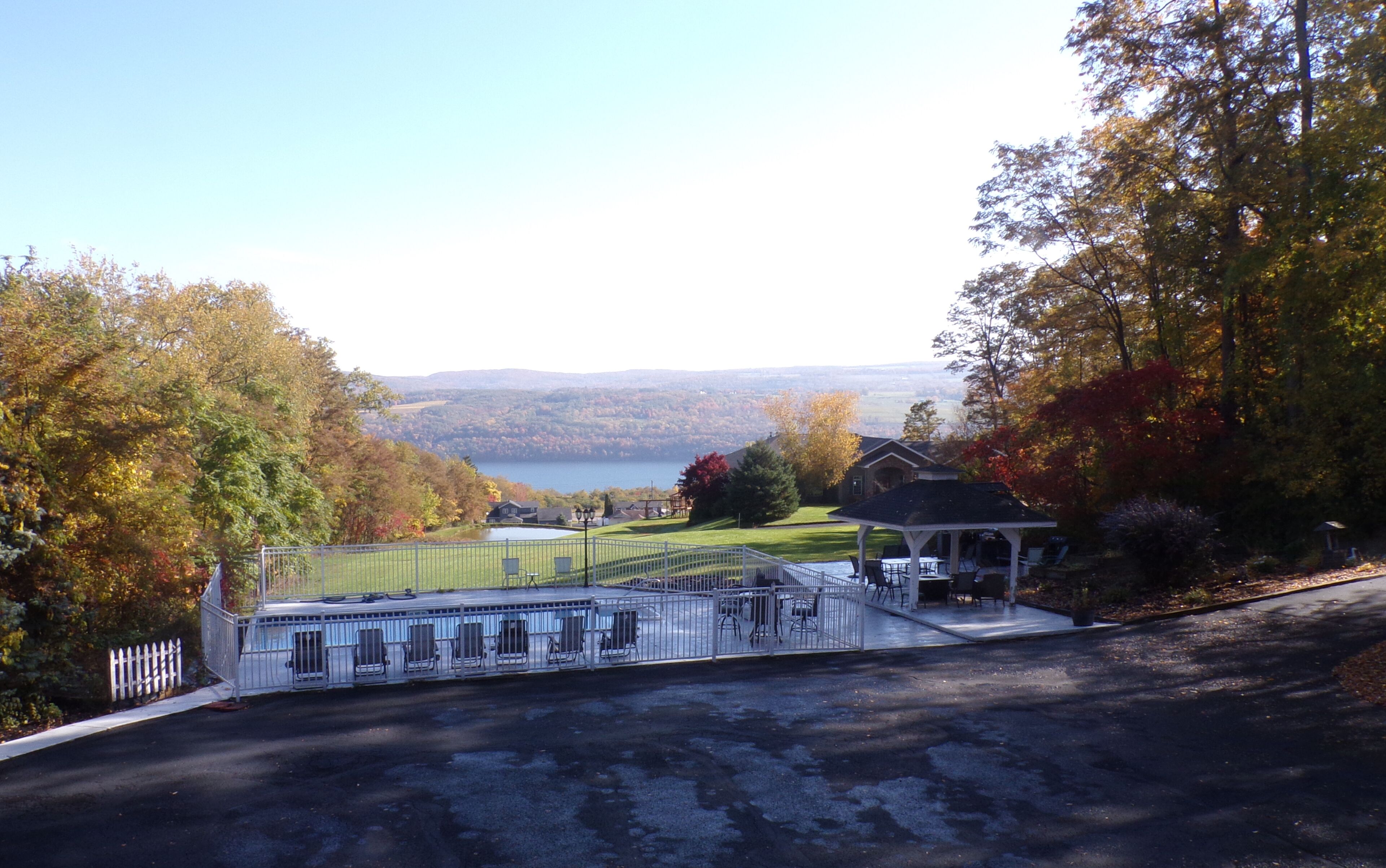 Vue d’une propriété dotée d’un belvédère, d’un espace salon extérieur et offrant une vue sur un lac et des collines.