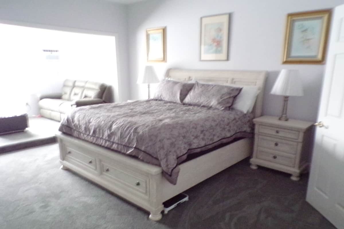 Une chambre à coucher comprenant un lit, des tables de chevet, une commode et une chaise.