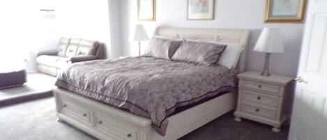 A bedroom with a bed, nightstands, a dresser, and a chair.