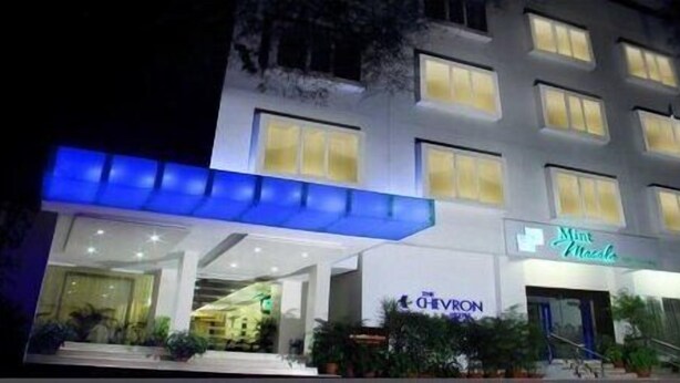 A hotel with a modern facade, a visible entrance, and signage for 'The Chevron' and 'Mint Mesa'. - The Chevron Hotel (Bengaluru)