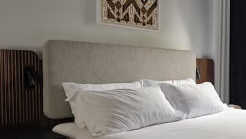 Una cama bien hecha con sábanas blancas, un cabecero con estampado geométrico y una obra de arte colgada en la pared.