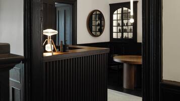 A modern interior with a dark-toned reception desk, a round mirror, and a wooden-framed window.