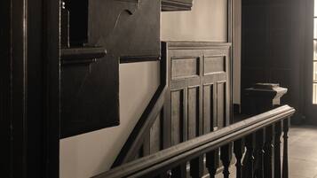 A staircase with dark wooden balusters and a handrail, leading to an arched doorway.