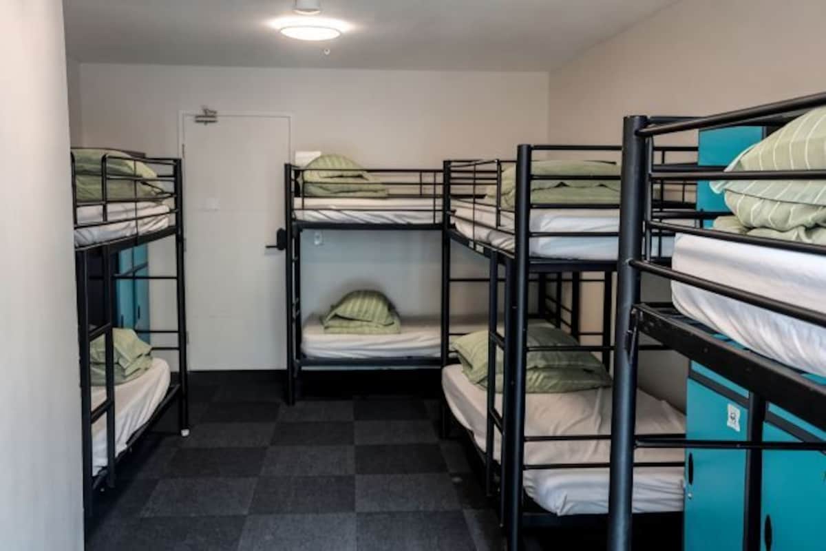 A dormitory room with bunk beds, a door, and a checkered floor.