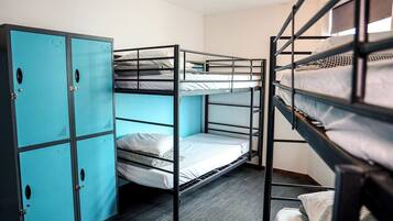 A bunk room with three bunk beds, a set of blue lockers, and a carpeted floor.