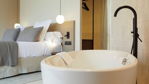 A modern bedroom with a large bathtub, a bed with white linens, and a wall-mounted control panel. -  1881 Hotel Balneario Vichy Catalan (Caldes de Malavella)