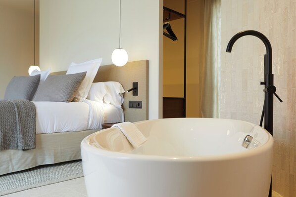 A modern bedroom with a large bathtub, a bed with white linens, and a wall-mounted control panel. -  1881 Hotel Balneario Vichy Catalan (Caldes de Malavella)
