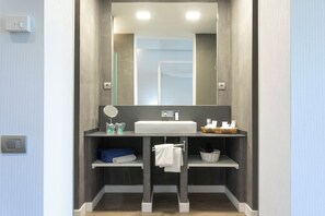 A modern bathroom with a large mirror, a white sink, and two shelves with towels and toiletries. -  1881 Hotel Balneario Vichy Catalan (Caldes de Malavella)