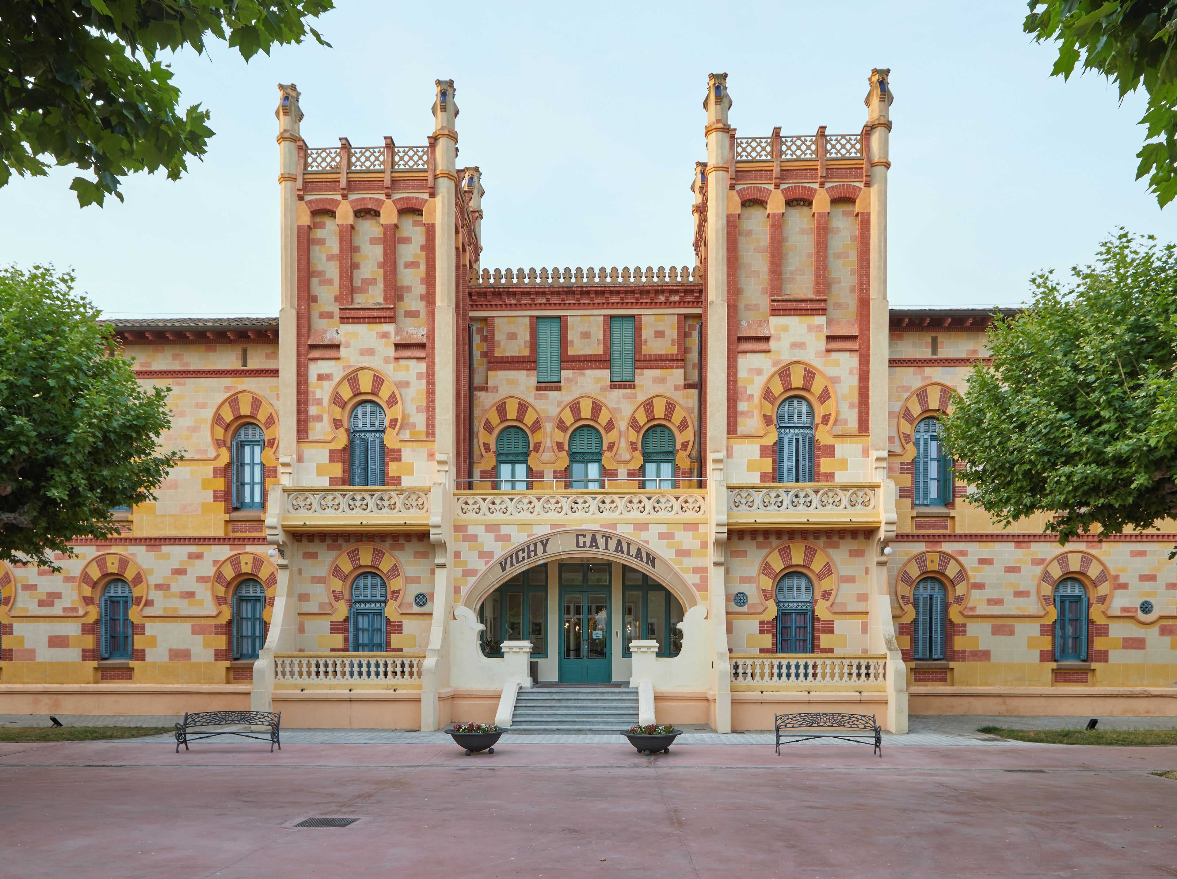 A building with a symmetrical facade, multiple arched windows, and a central entrance with steps leading up to it.