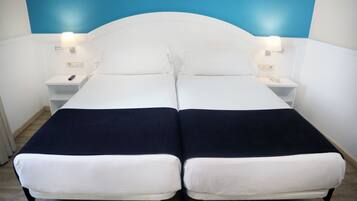 A double bed with white and navy bedding, two bedside tables with lamps, and a blue accent wall.