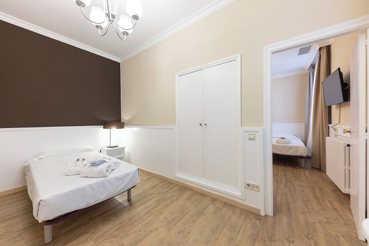 A bedroom with a bed, bedside table, wardrobe, and a television mounted on the wall.