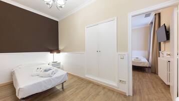 A bedroom with a bed, bedside table, wardrobe, and a television mounted on the wall.