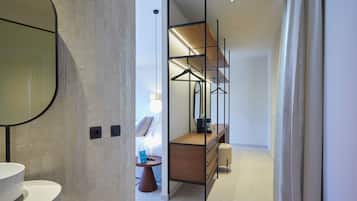 Un baño moderno con un espejo redondo, un lavamanos blanco y un tocador de madera.