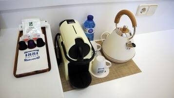 A kitchenette with a coffee maker, tea kettle, and a tray with coffee cups and a water bottle.