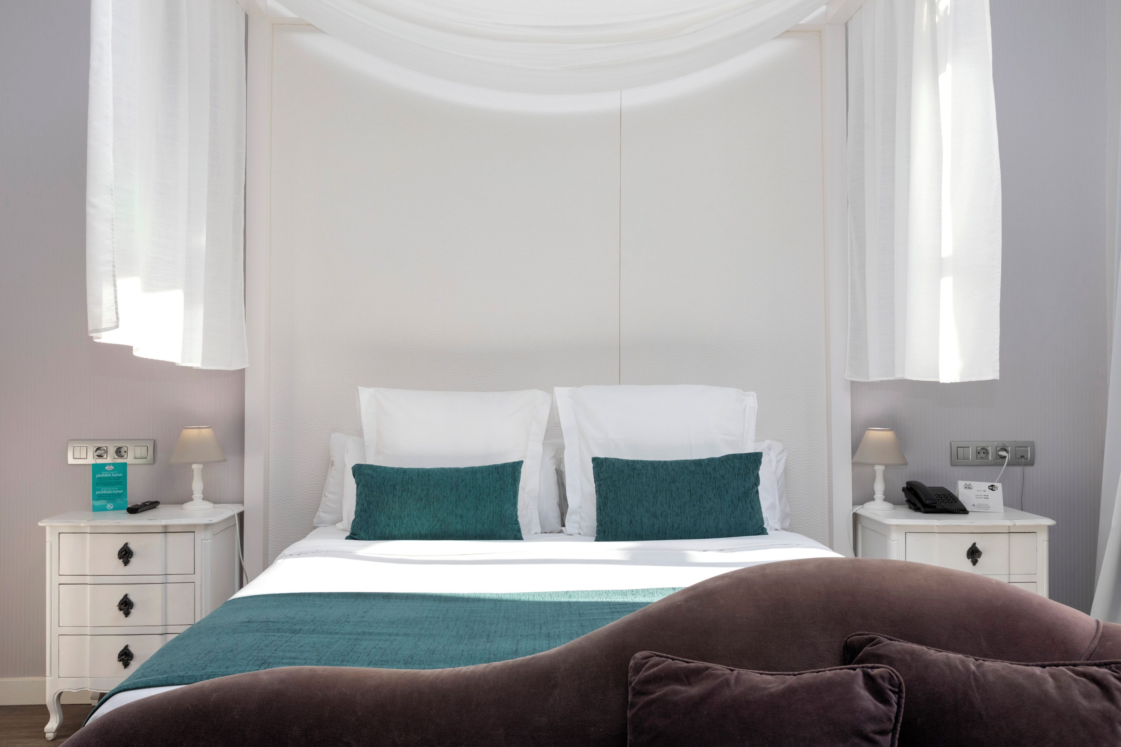Une chambre à coucher avec un lit, deux tables de chevet, une commode et une lampe.