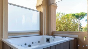 A hot tub with a window view, wooden deck, and a stone wall. -  1881 Hotel Balneario Vichy Catalan (Caldes de Malavella)
