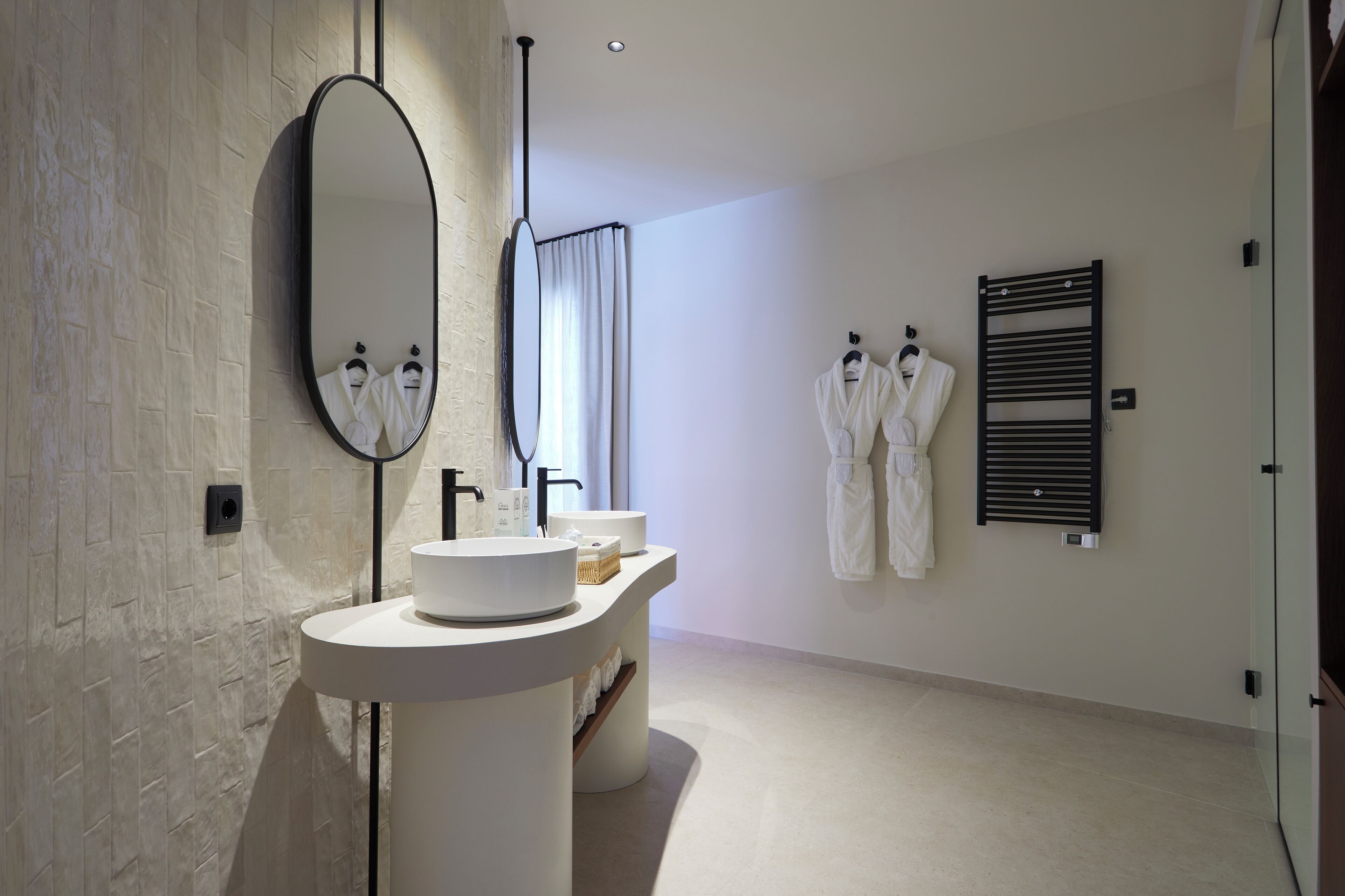Un baño moderno con tocador blanco, un espejo grande y un perchero para toallas.
