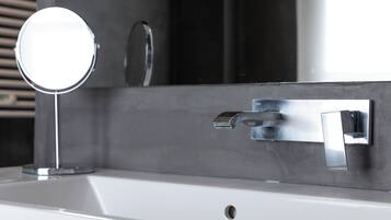 Un lavabo de salle de bain avec un miroir rond, un robinet chromé et un porte-serviettes fixé au mur.