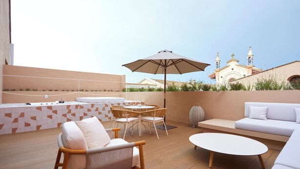 Eine Dachterrasse mit Sitzgelegenheit, darunter eine Couch, Stühle und ein Tisch.