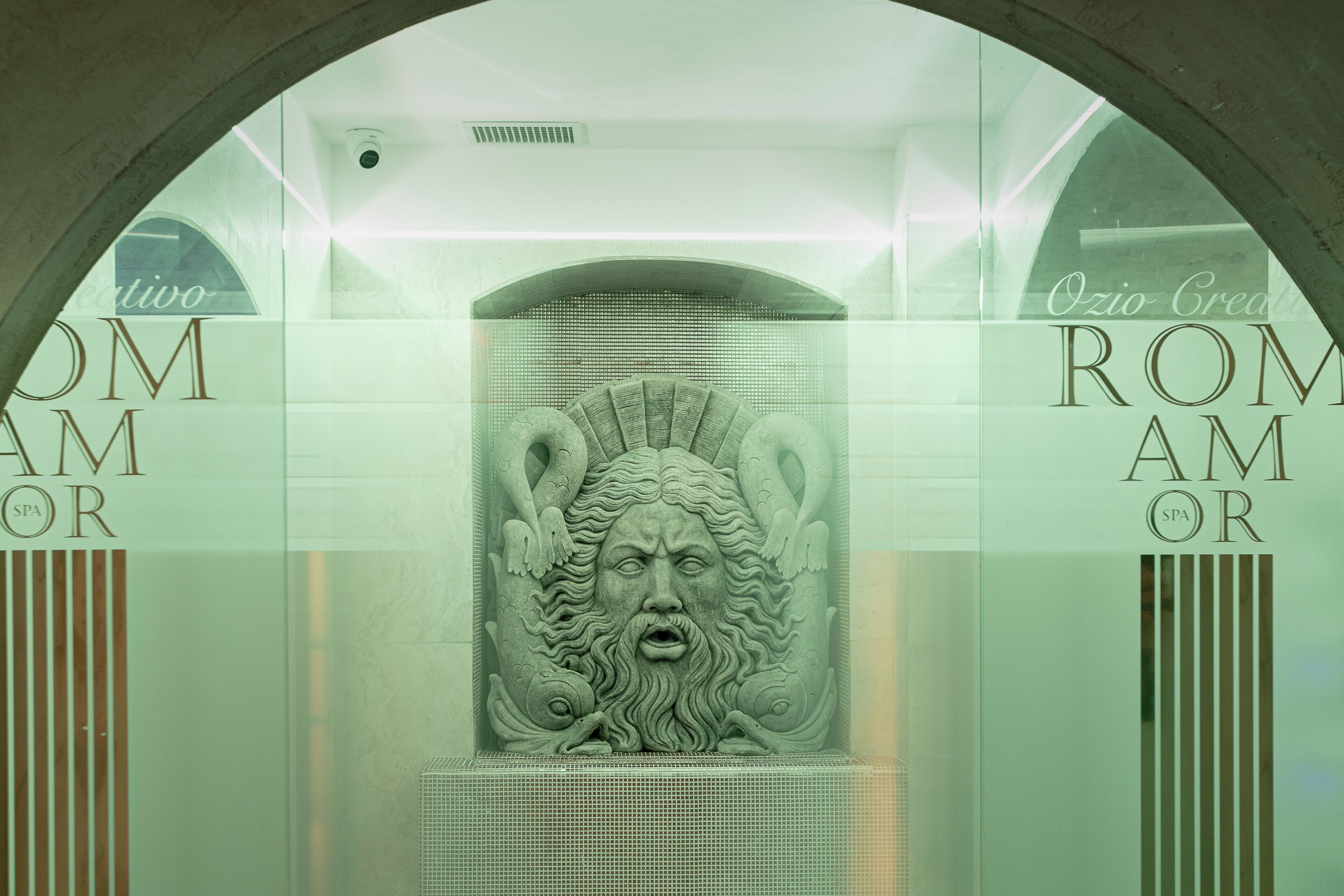 Een spa met een grote, gewelfde ingang, een centraal reliëf en de tekst 'ROMAN SPA' op de muren.