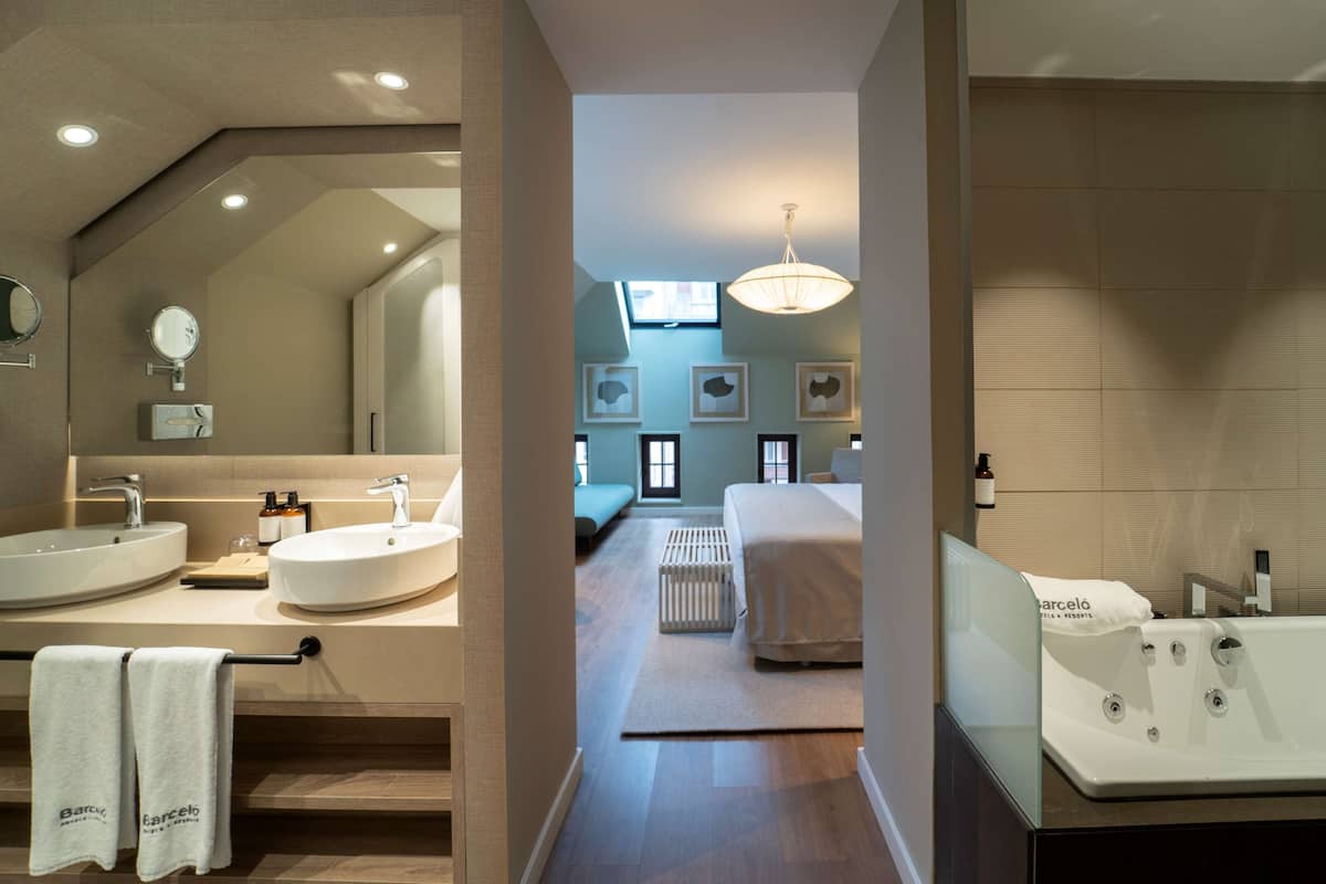 Een moderne badkamer met dubbele wastafels, een grote spiegel en een bad.