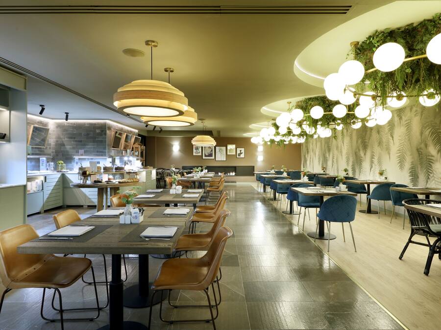 Um restaurante moderno com mesas comunitárias grandes, cabines individuais e diversos tipos de luminárias.