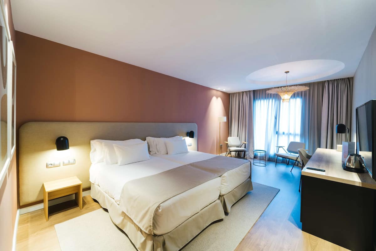Een hotelkamer met een groot bed, nachtkastjes, een bureau, een stoel en een televisie.