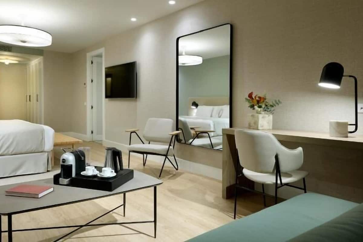 Een hotelkamer met een bed, bureau, stoel, koffiezetapparaat en televisie.