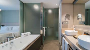 A modern bathroom with a large bathtub, a double sink, and a large mirror.