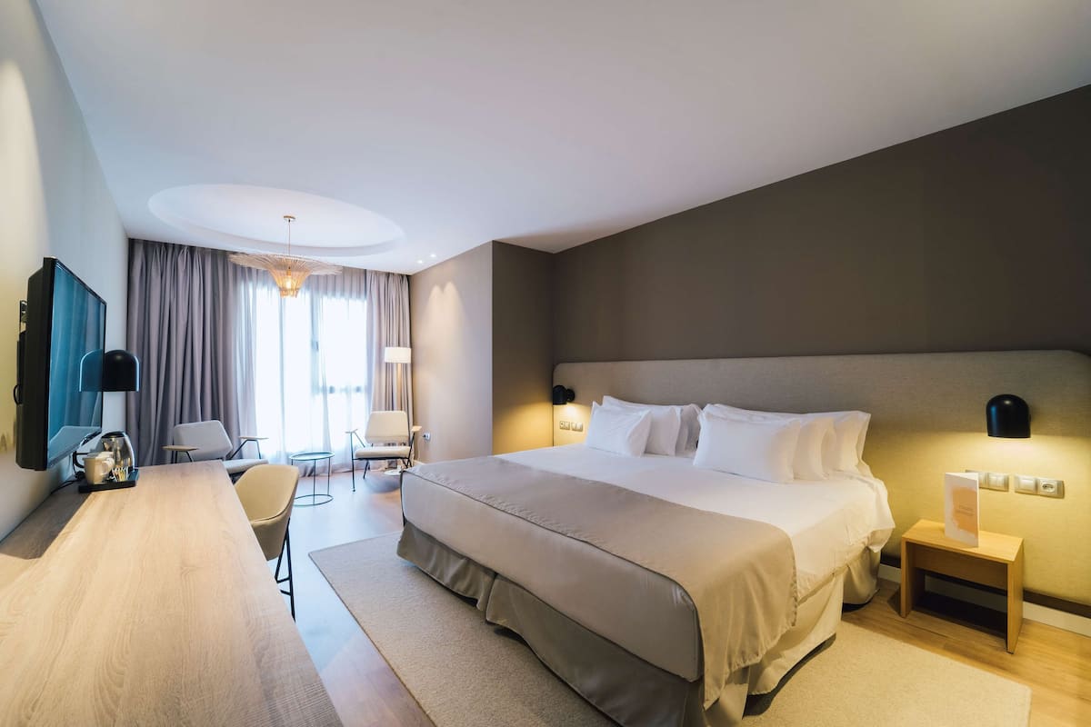 Een moderne hotelkamer met een groot bed, een bureau, een stoel en een televisie.