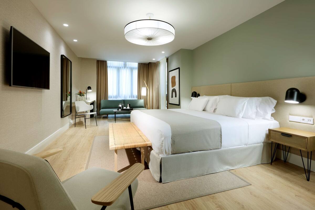 Een moderne hotelkamer met een groot bed, een bureau, een stoel en een televisie.