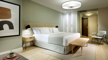 Habitación de hotel moderna con una cama grande, mesitas de noche, lámparas de noche, una pequeña mesa y una silla.
