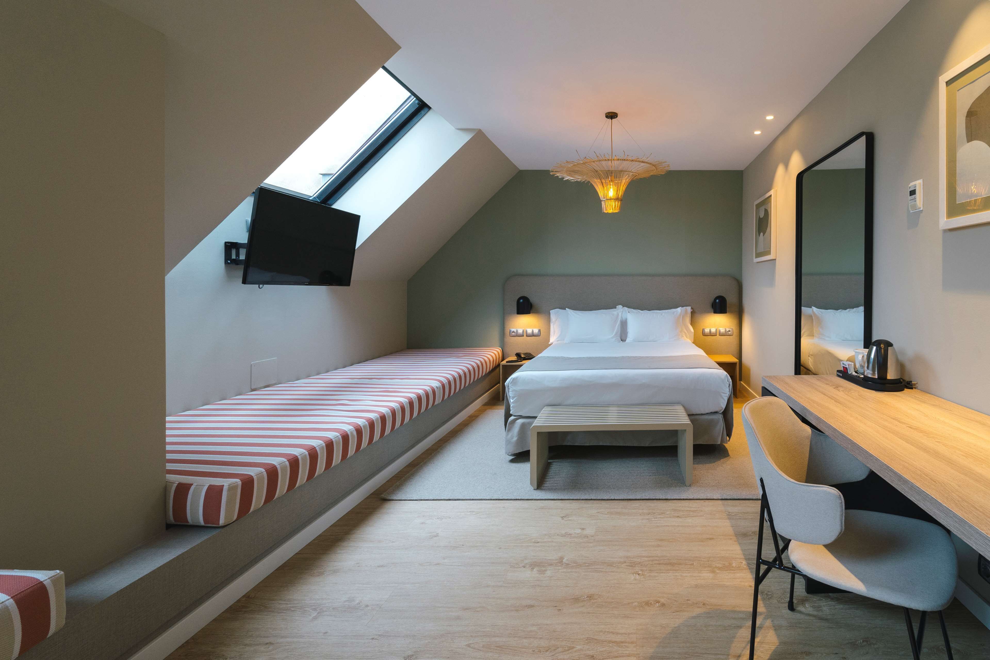 A modern bedroom with a skylight, a bed, a desk, and a chair.