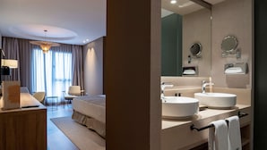 A hotel room with a bed, bedside table, lamp, and a desk with a sign.