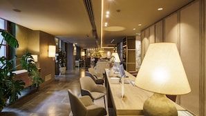 A hotel lobby with a reception desk, seating area, and a large lamp.
