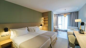 Una habitación de hotel con una cama grande, mesitas de noche, un escritorio y una silla.