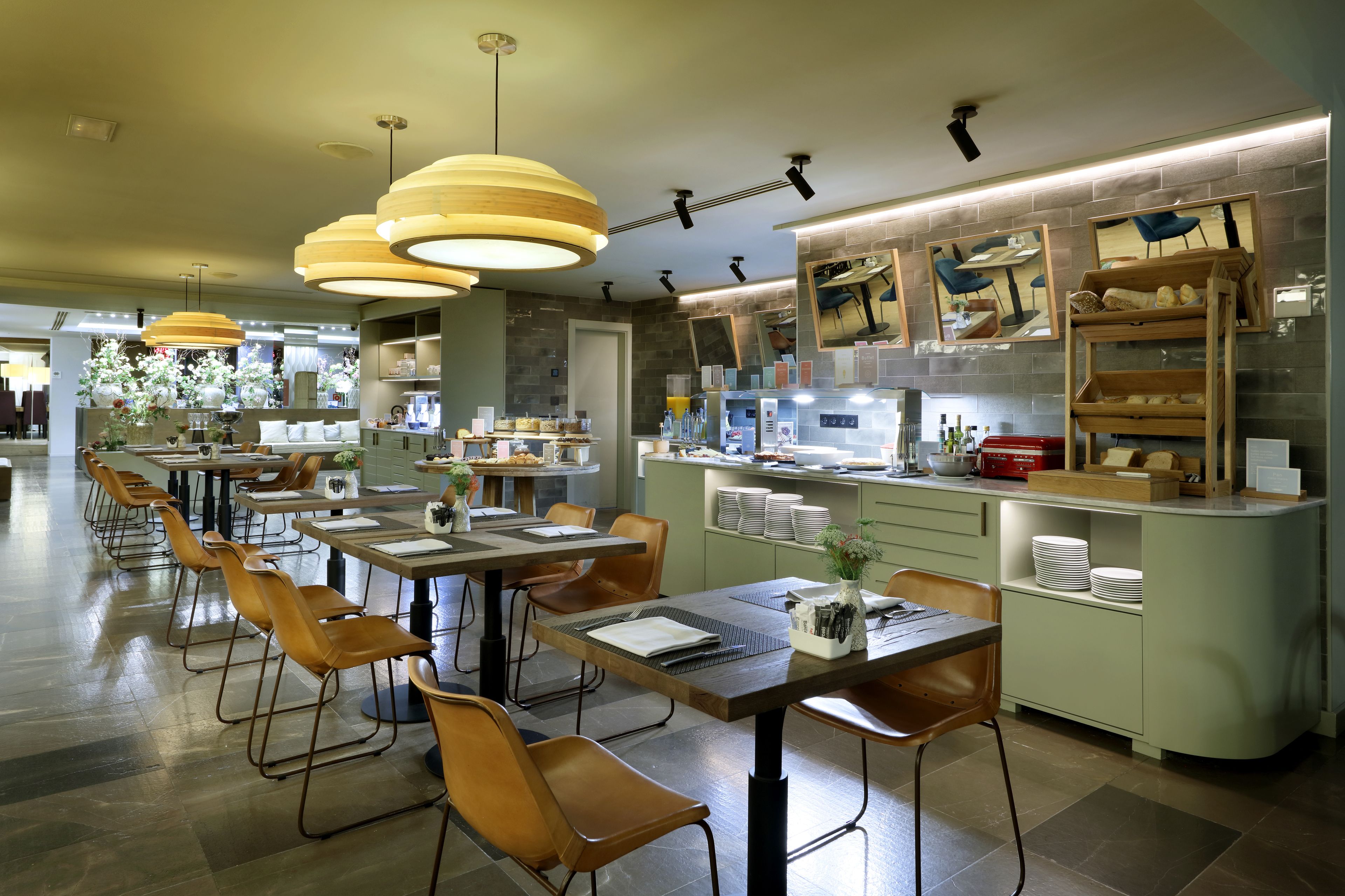 Ein modernes Restaurant mit langen Gemeinschaftstischen, Holzstühlen und Pendelleuchten.