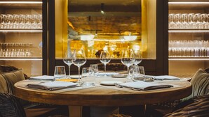 A restaurant setting with a round table set for dining, glasses, and cutlery.